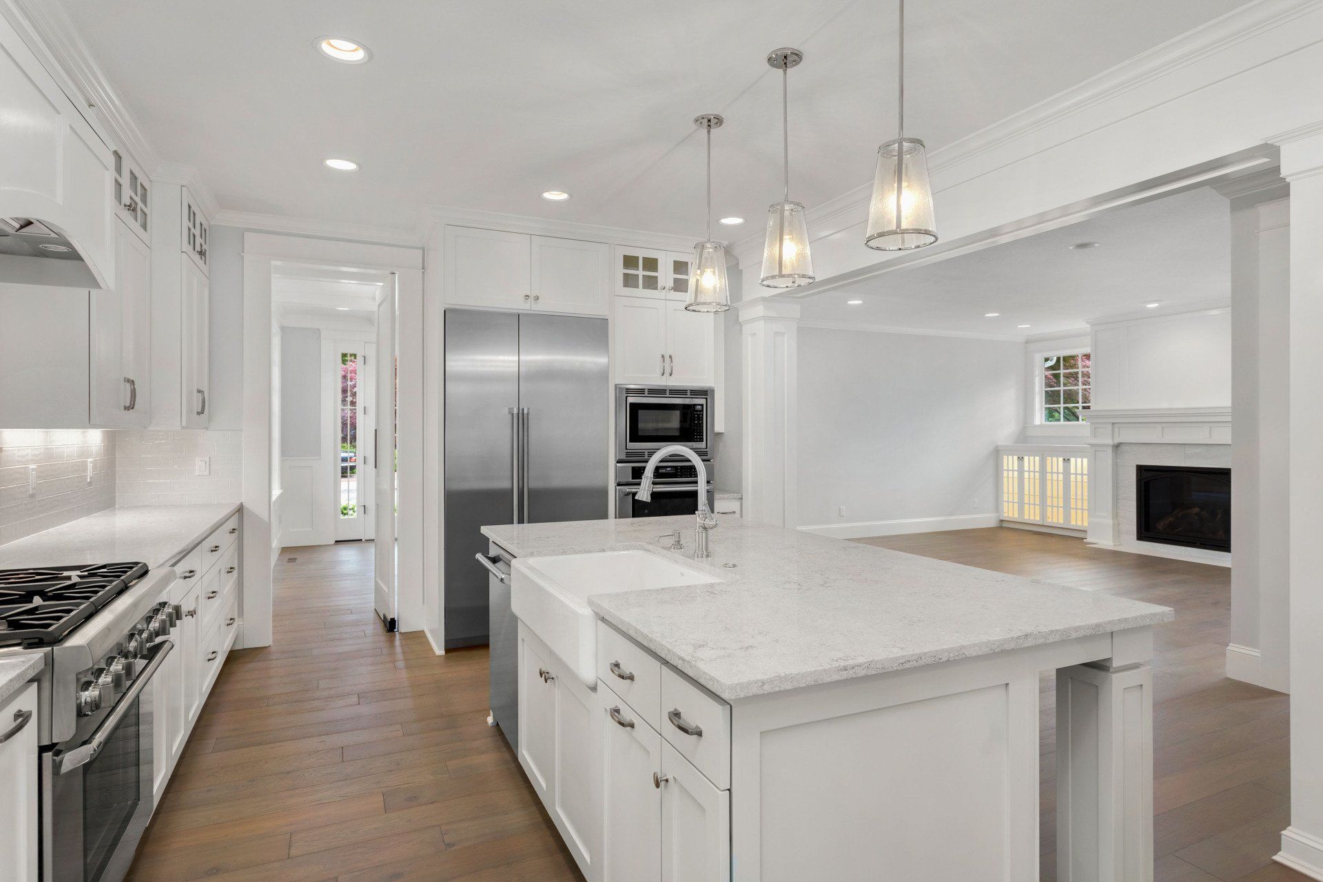 A kitchen with white cabinets , stainless steel appliances , and a large island.