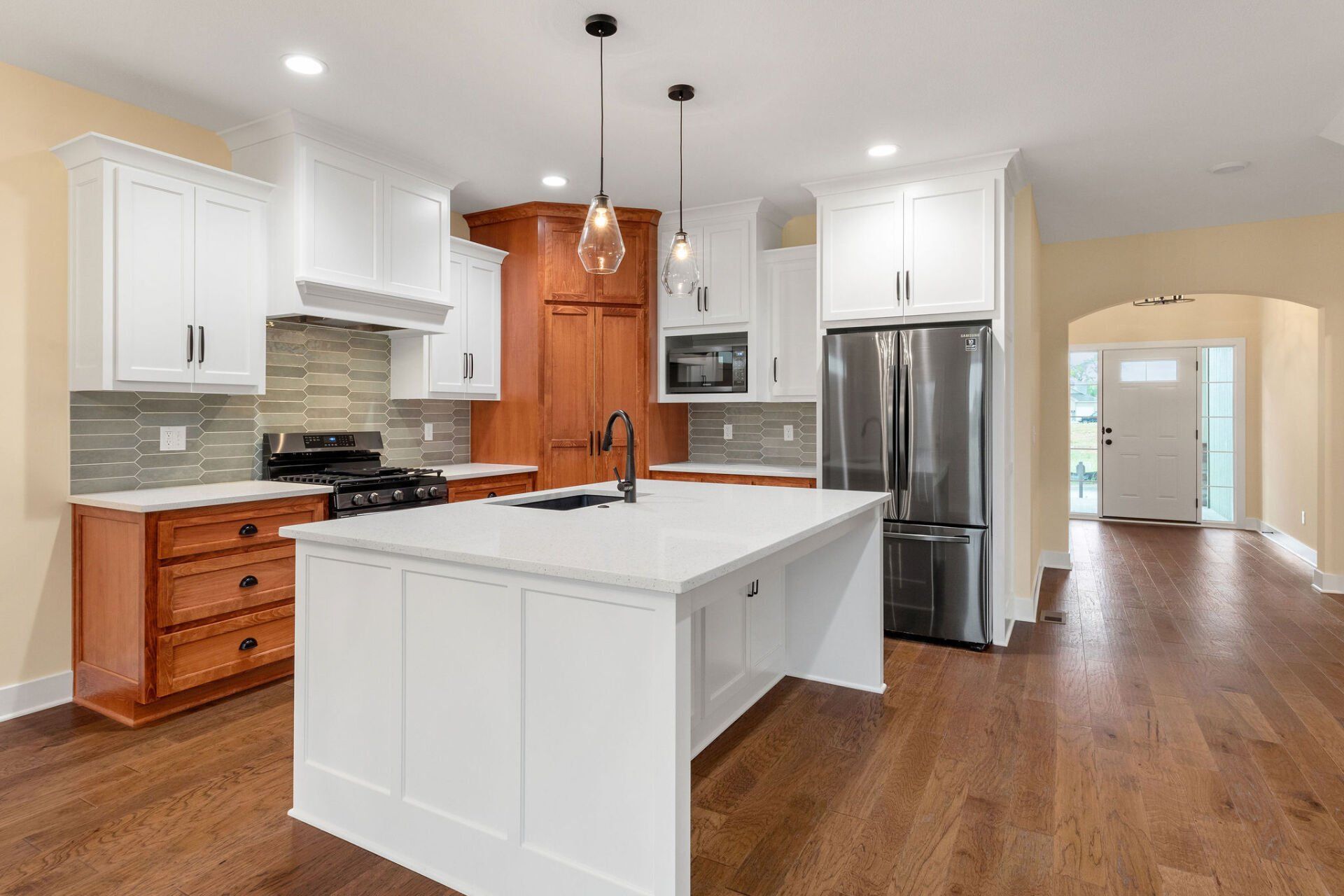 A kitchen with white cabinets and wooden floors and a large island in the middle.