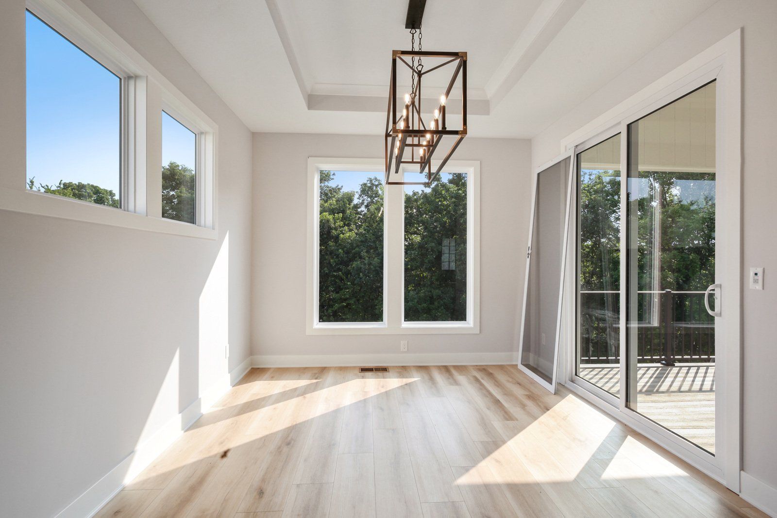 An empty room with sliding glass doors and a chandelier hanging from the ceiling.