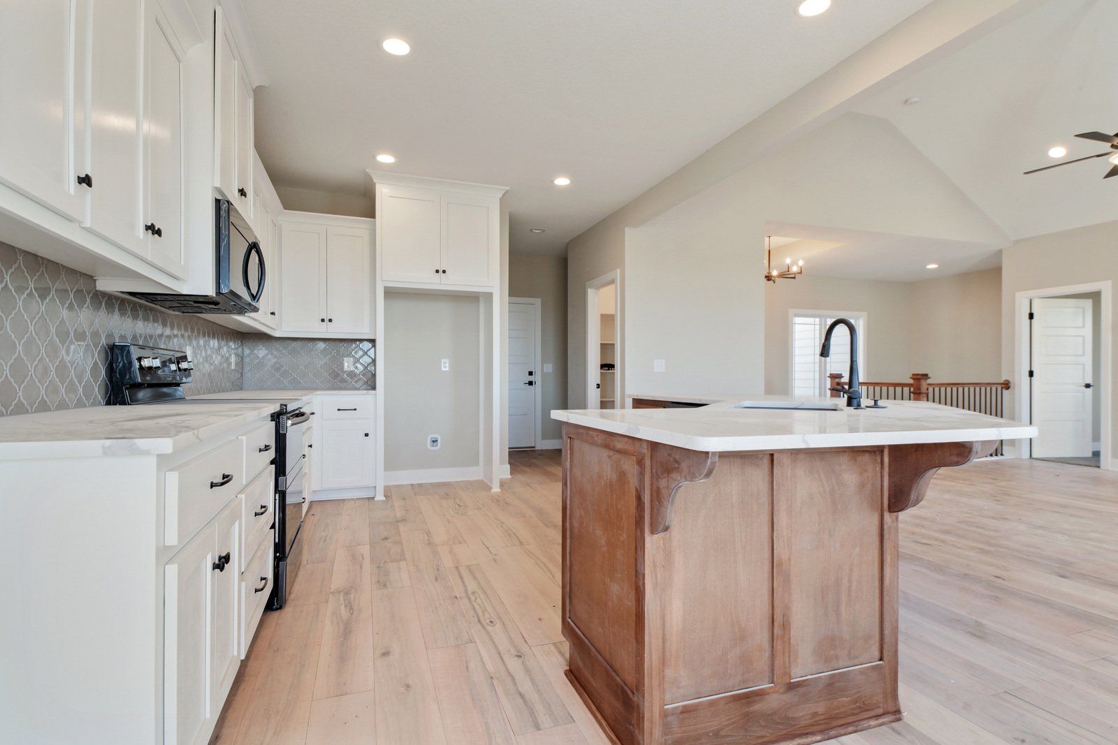 A kitchen with white cabinets and a large wooden island.