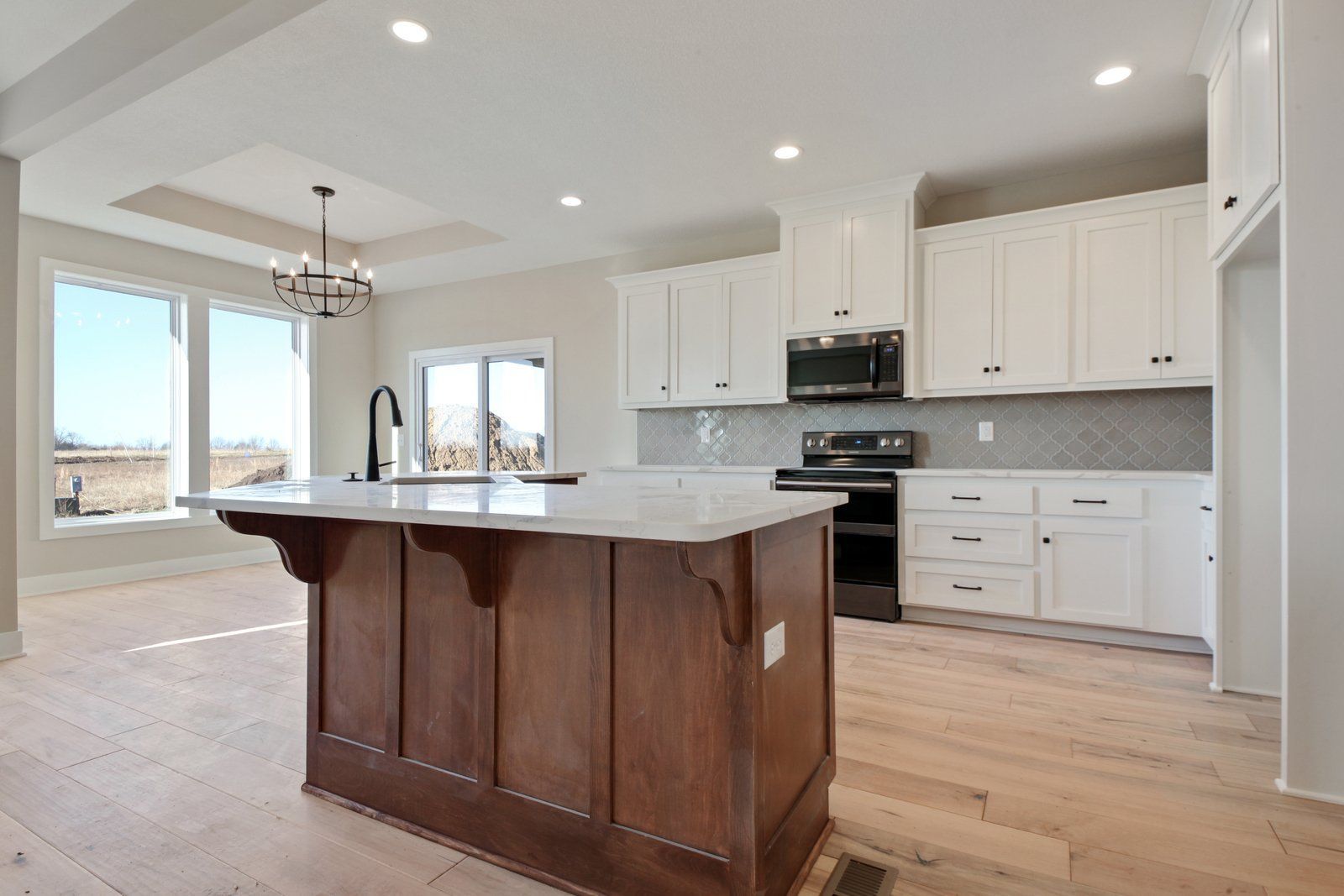 A kitchen with white cabinets and a large island in the middle.