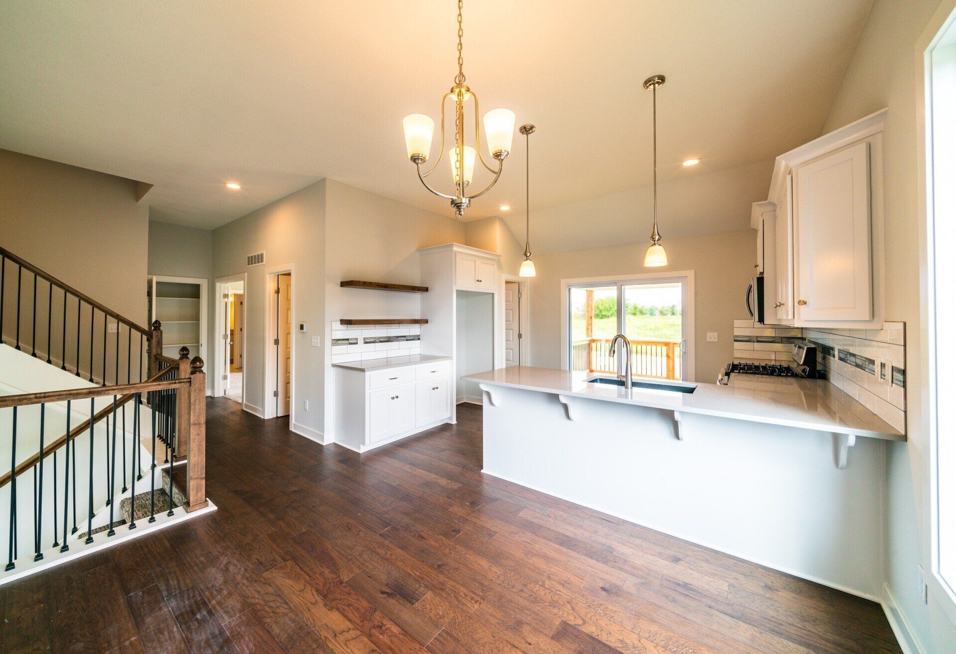 A kitchen with white cabinets and hardwood floors and a chandelier hanging from the ceiling.