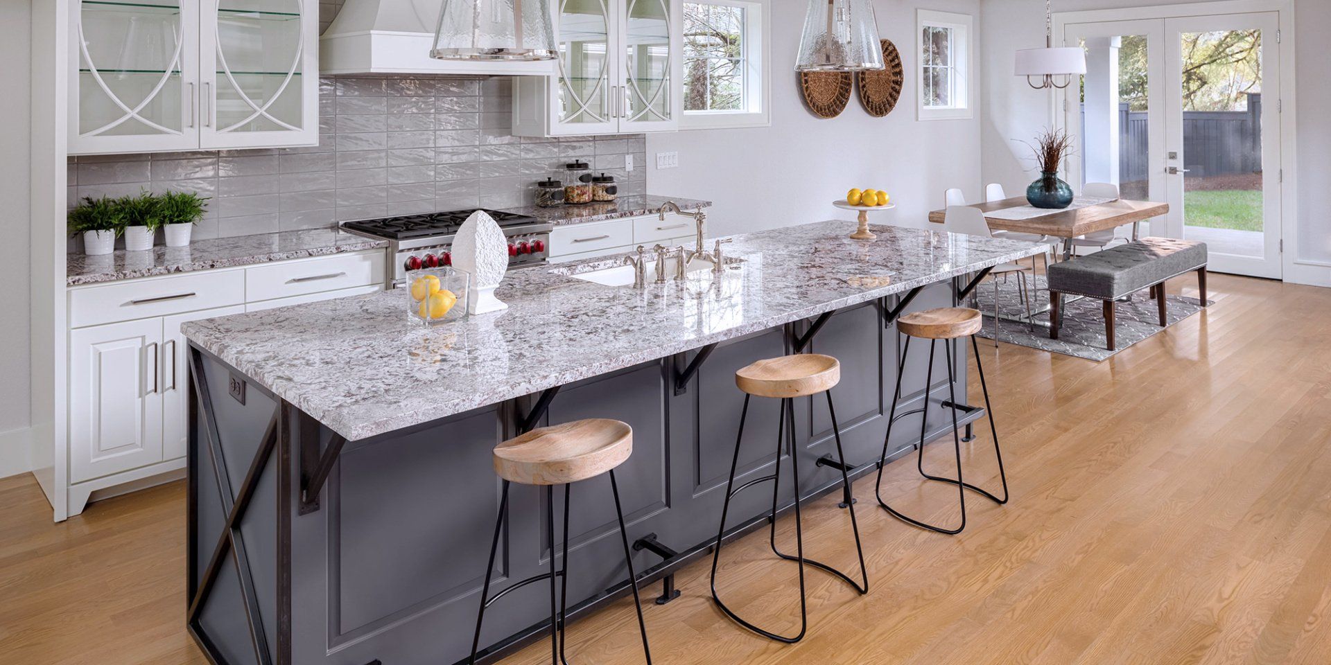 A kitchen with a large island and stools and a wooden floor.
