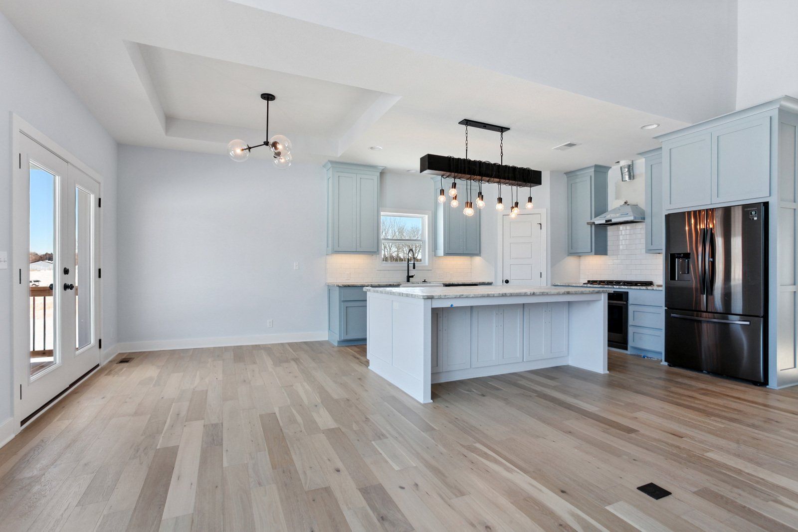 An empty kitchen with a large island and stainless steel appliances.