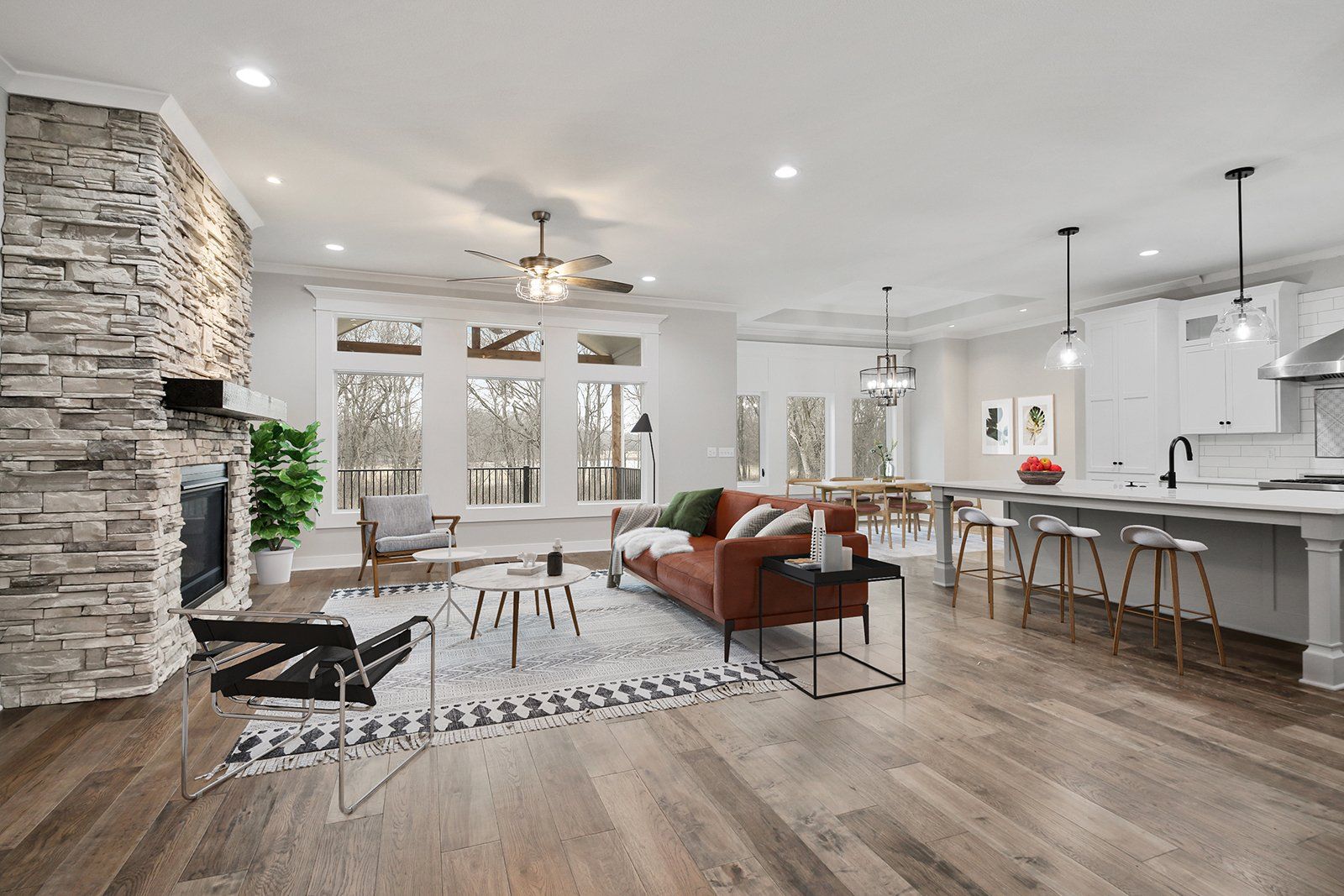 A living room with a couch , chairs , a fireplace and a kitchen.