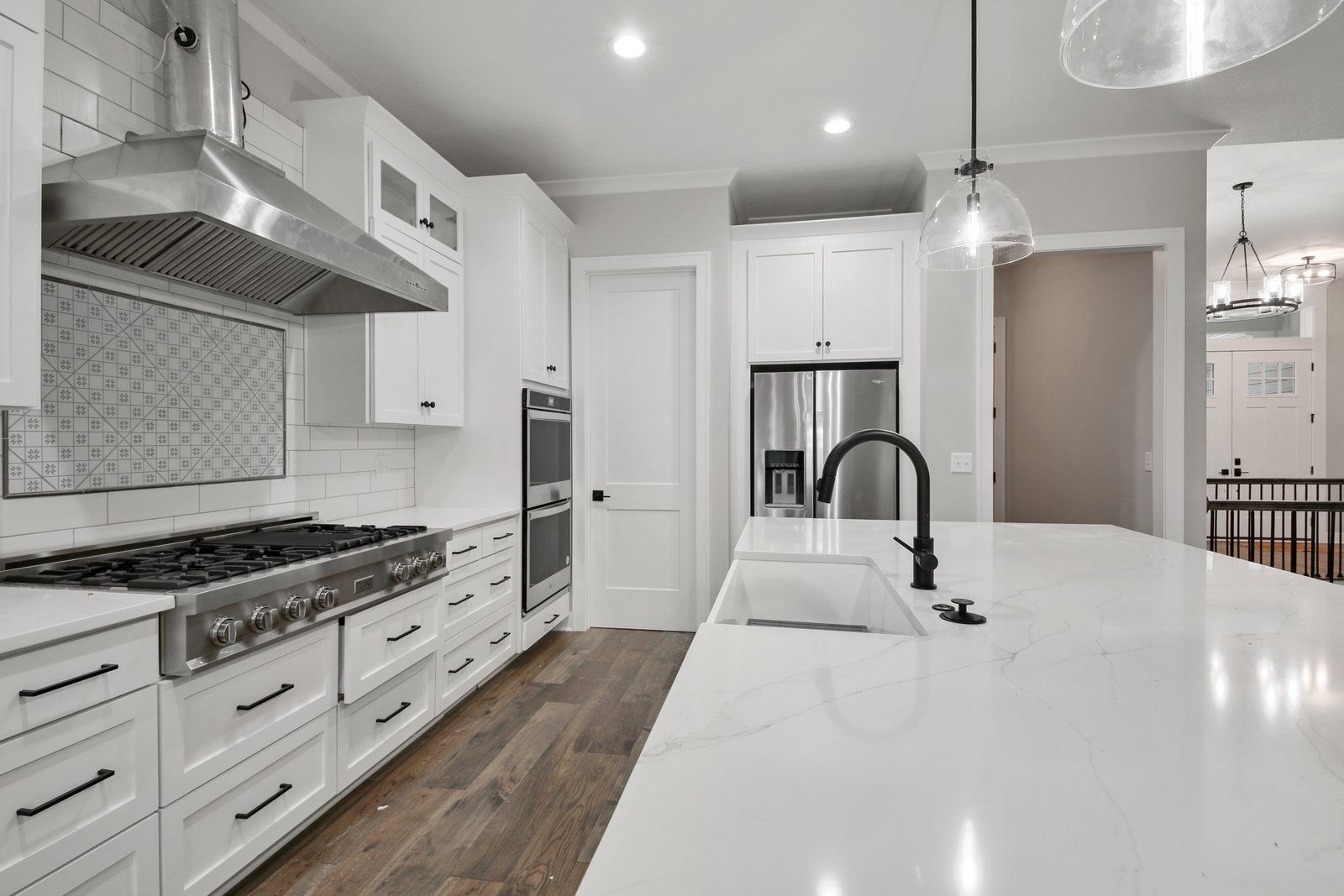 A kitchen with white cabinets , stainless steel appliances , and a large island.
