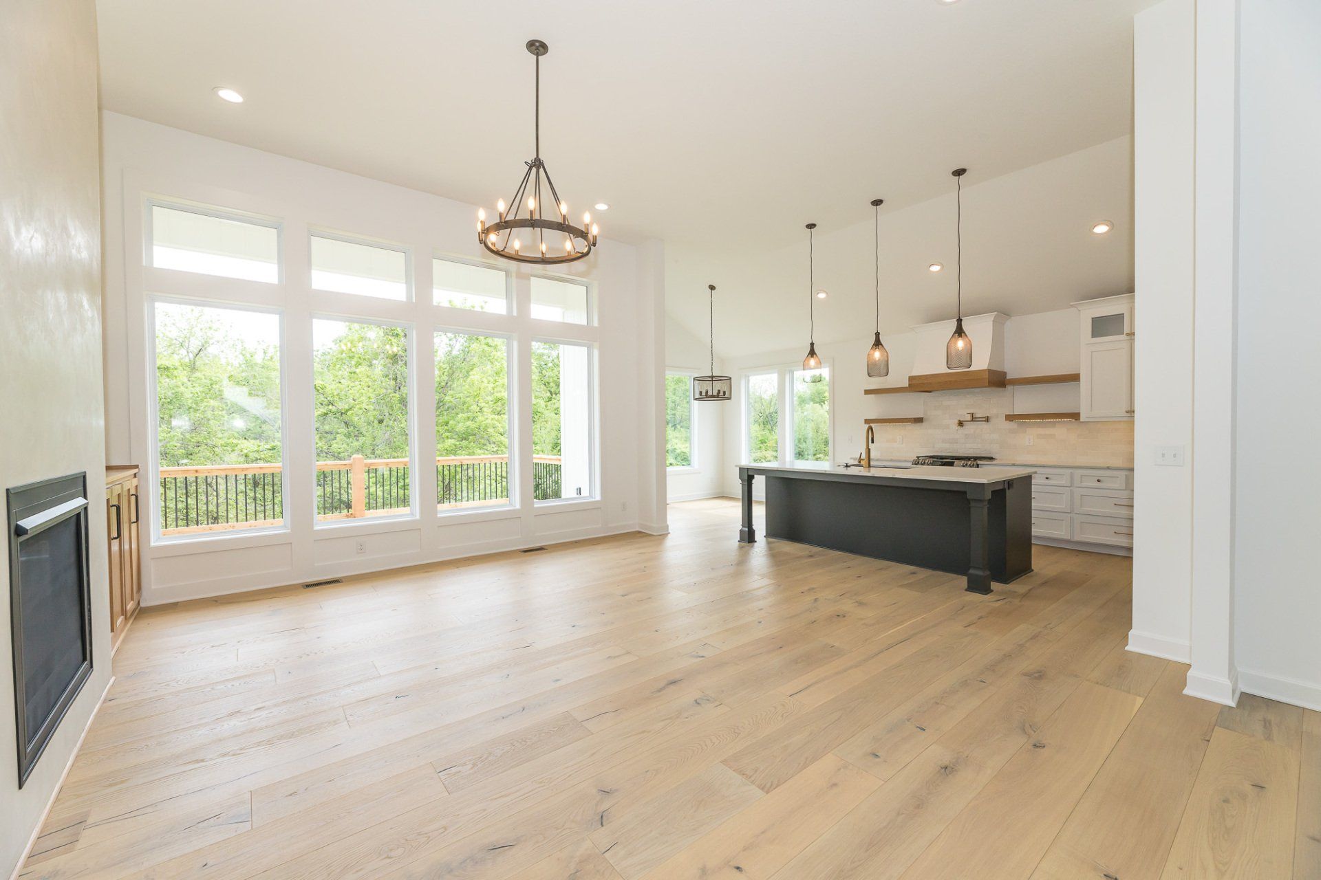 A large empty living room with hardwood floors and a kitchen.