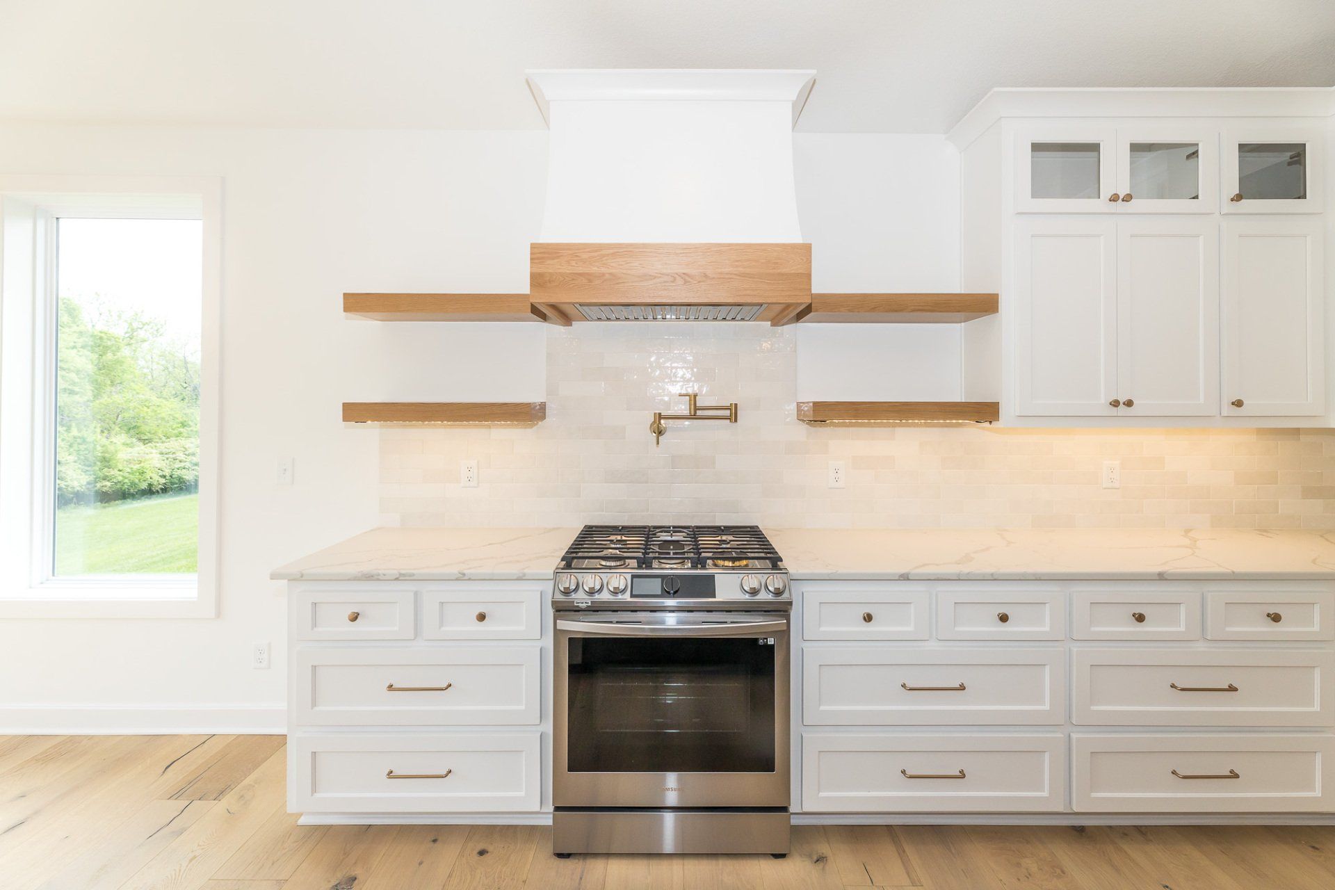 A kitchen with white cabinets , stainless steel appliances , and wooden shelves.