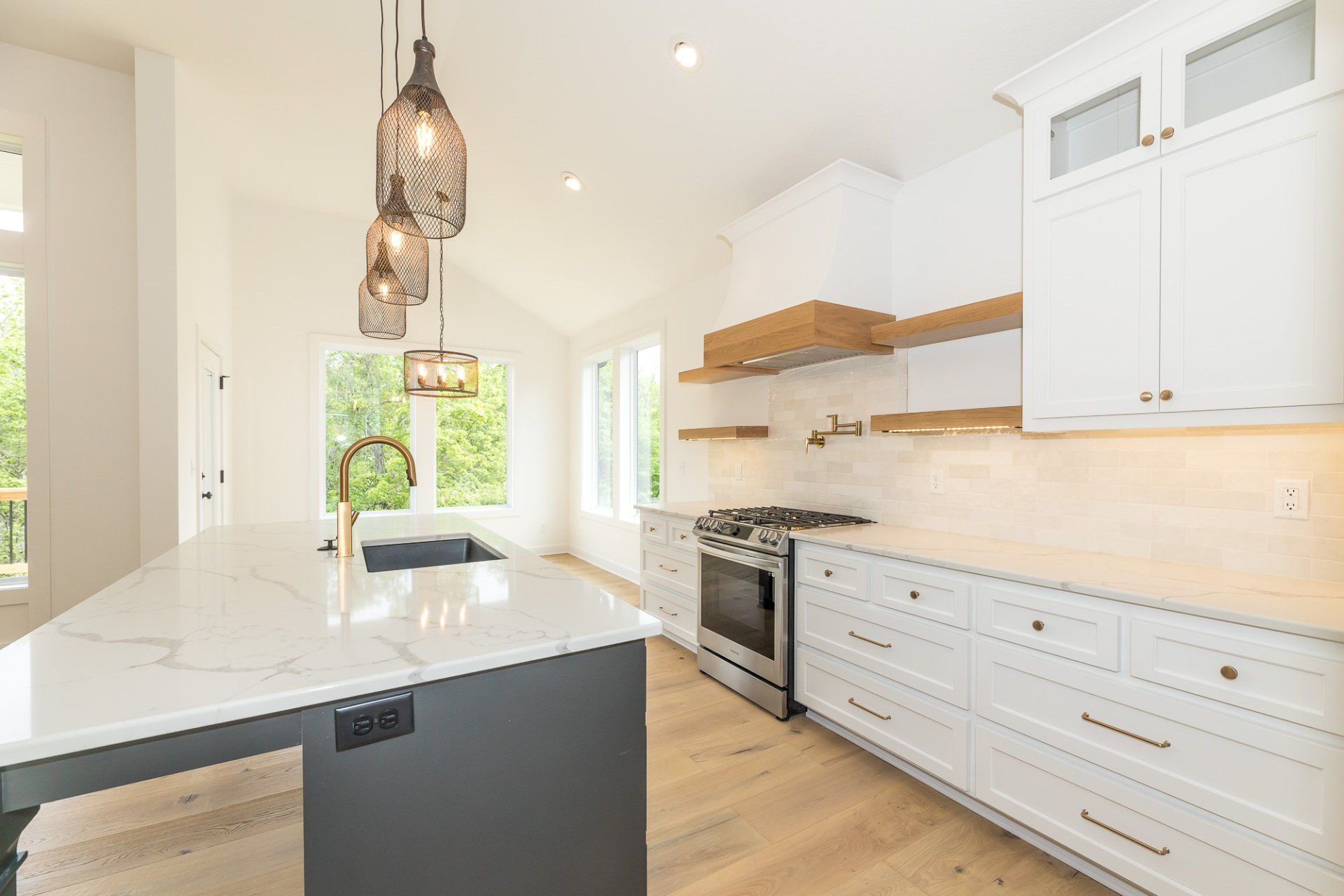 A kitchen with white cabinets , granite counter tops , stainless steel appliances and a large island.