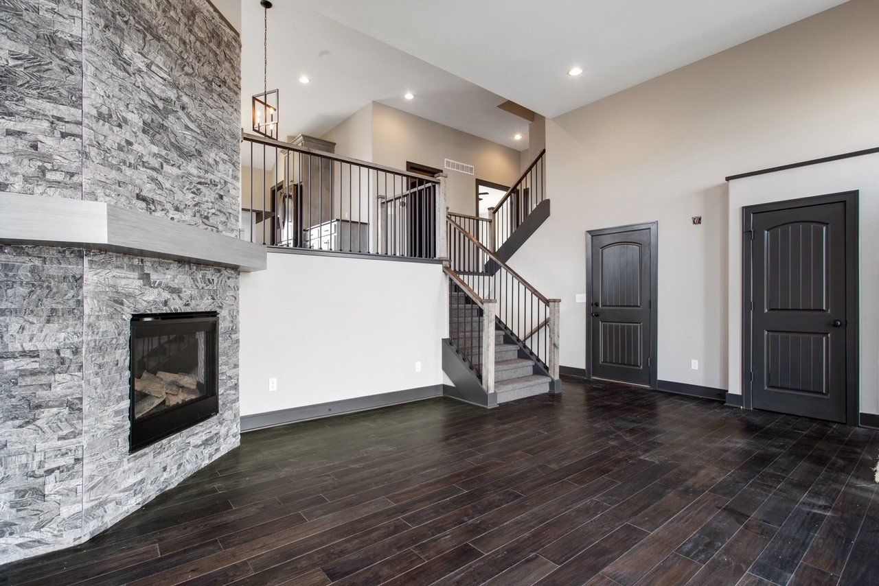 An empty living room with a fireplace and stairs