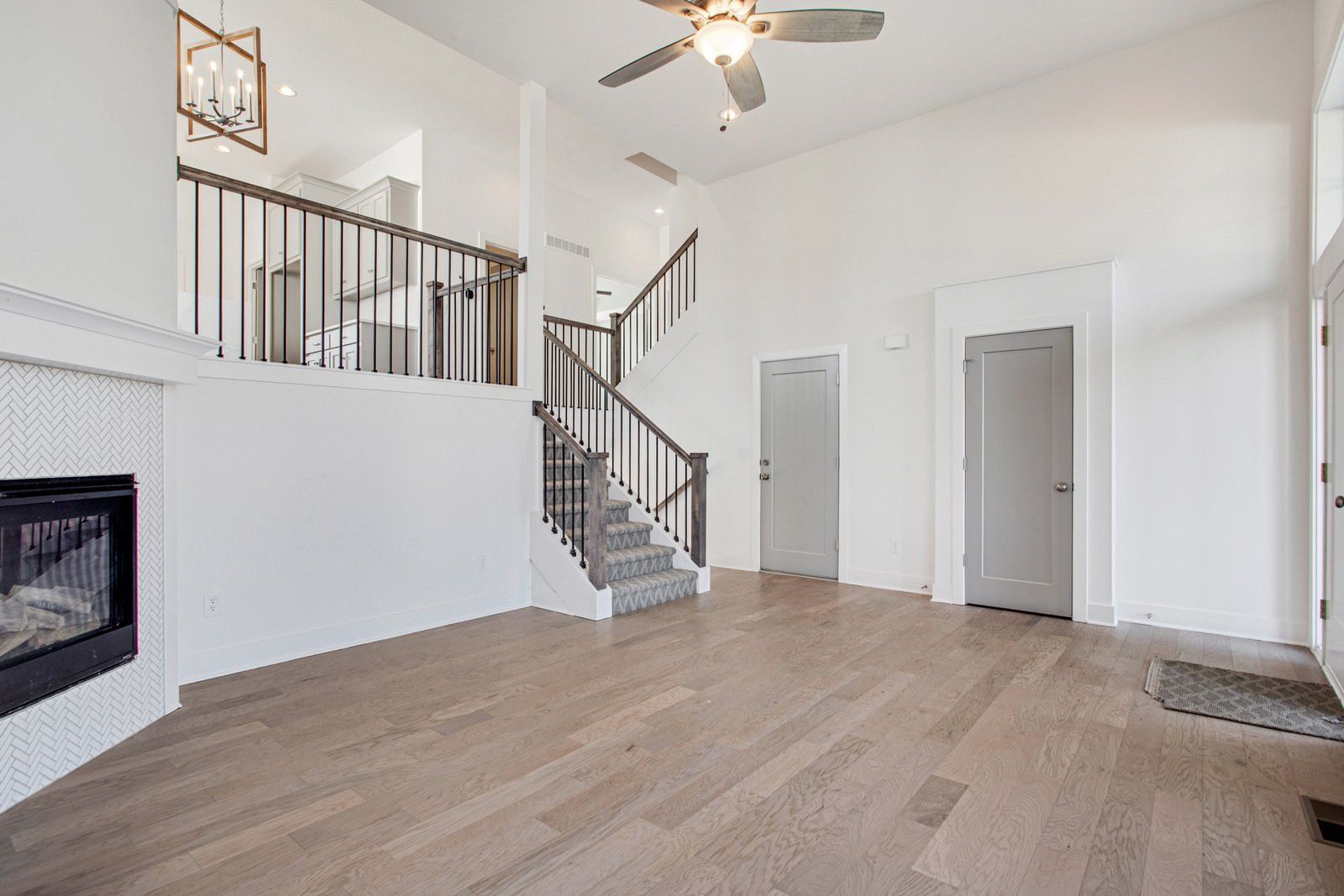 A living room with hardwood floors , a fireplace and a ceiling fan.