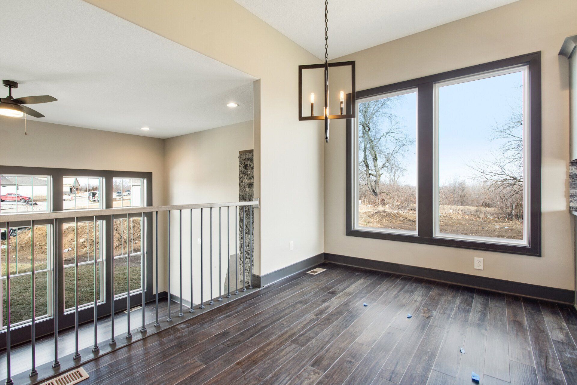An empty room with hardwood floors and a ceiling fan.