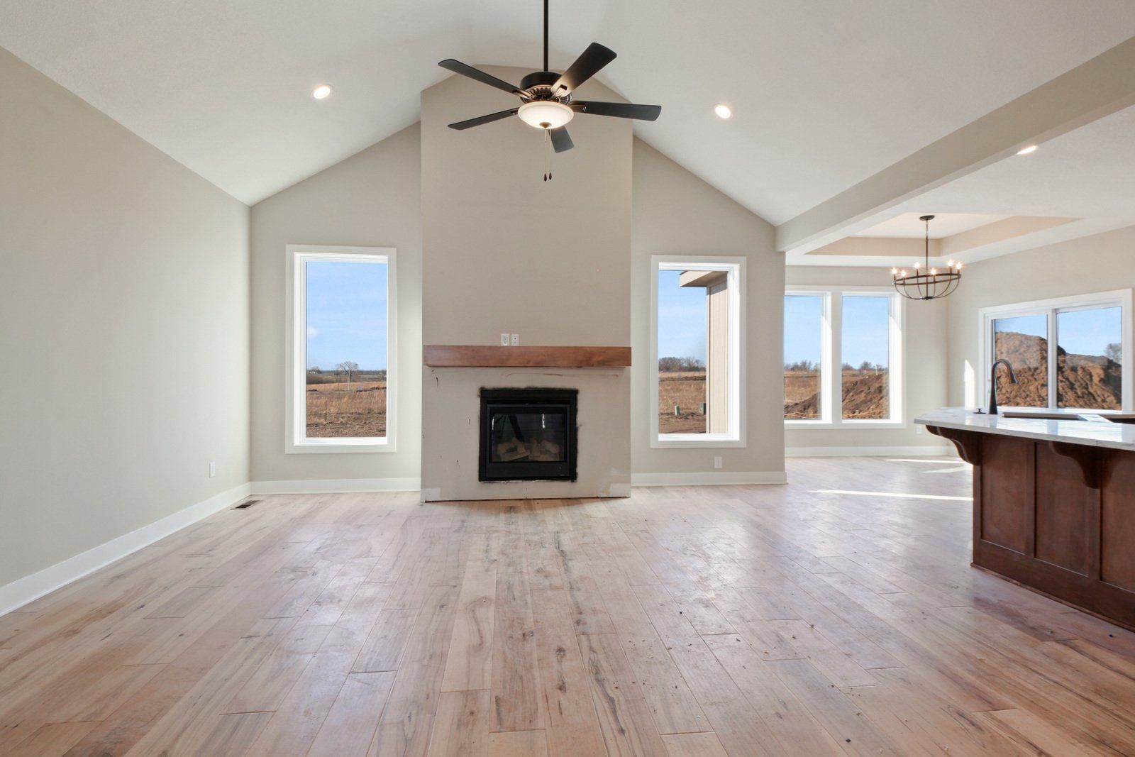 An empty living room with a fireplace and ceiling fan