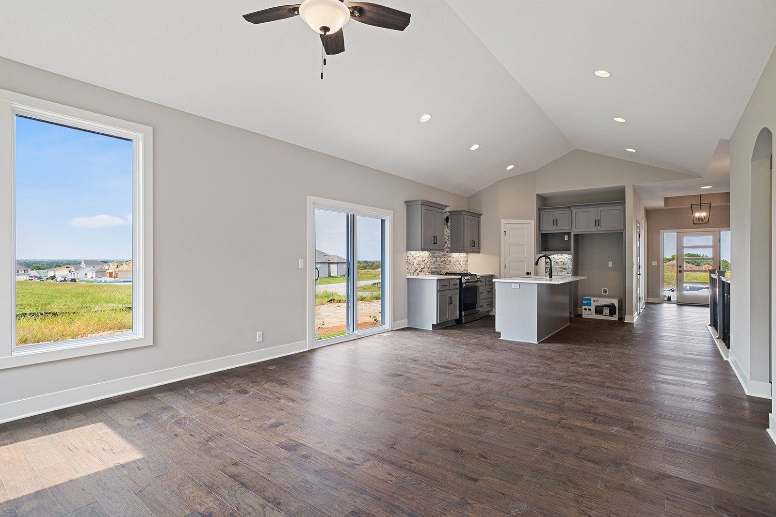 An empty living room with hardwood floors and a ceiling fan.