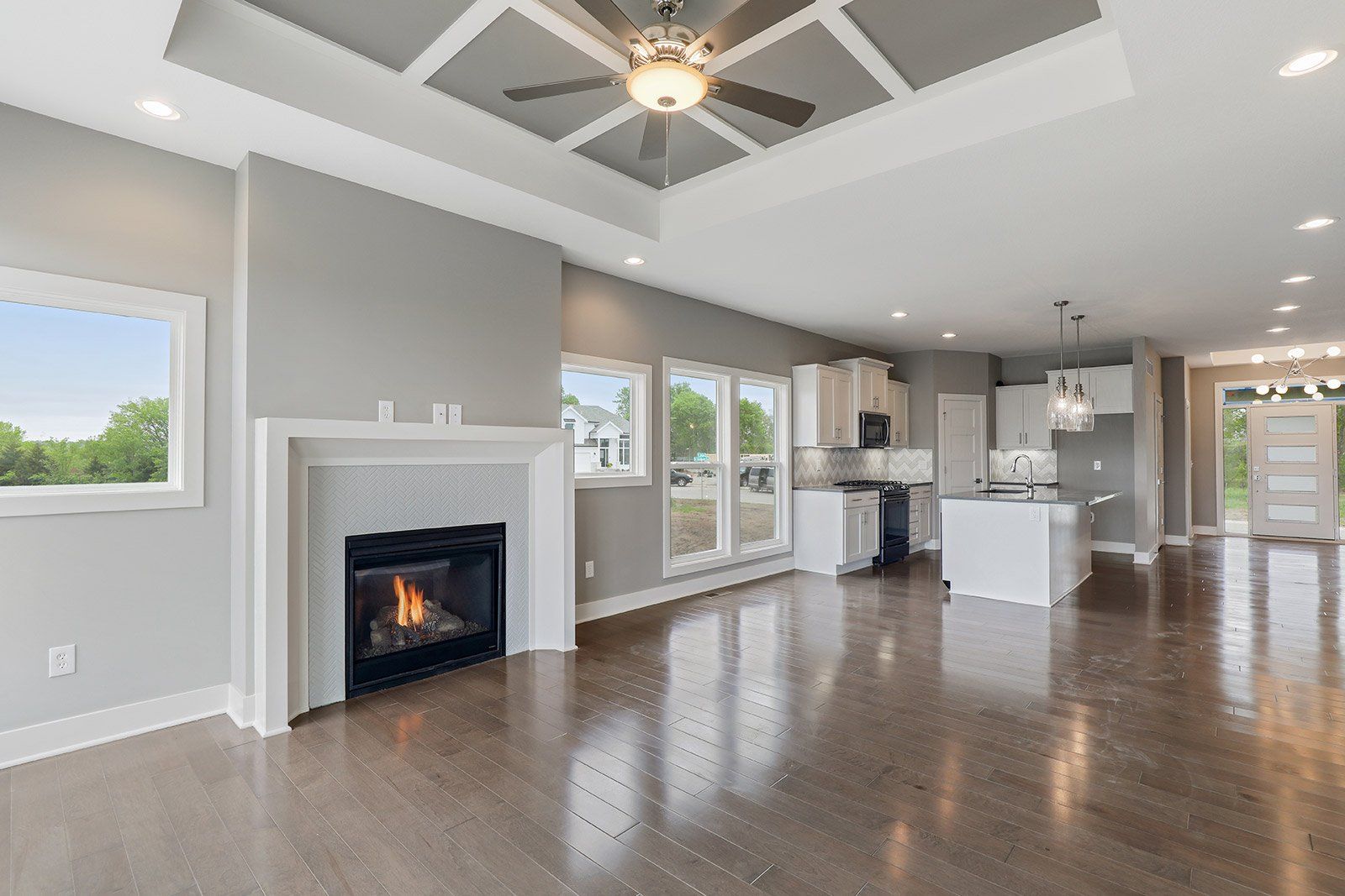 An empty living room with a fireplace and a ceiling fan.
