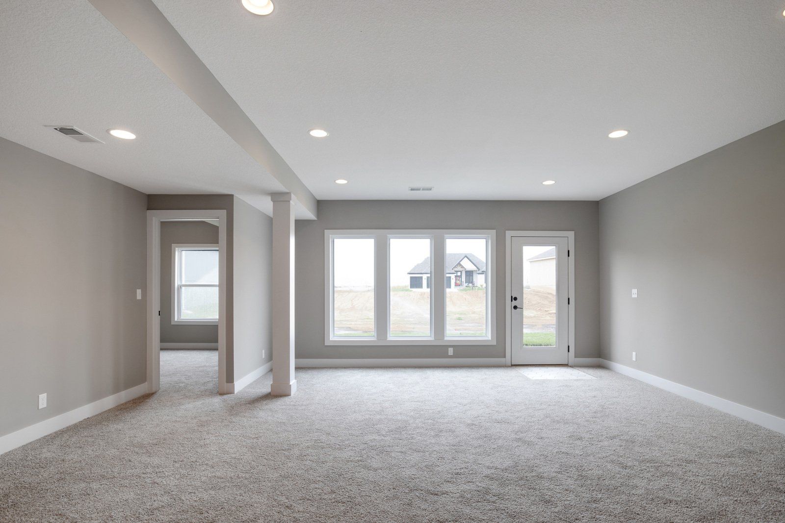 An empty basement with a lot of windows and carpet.