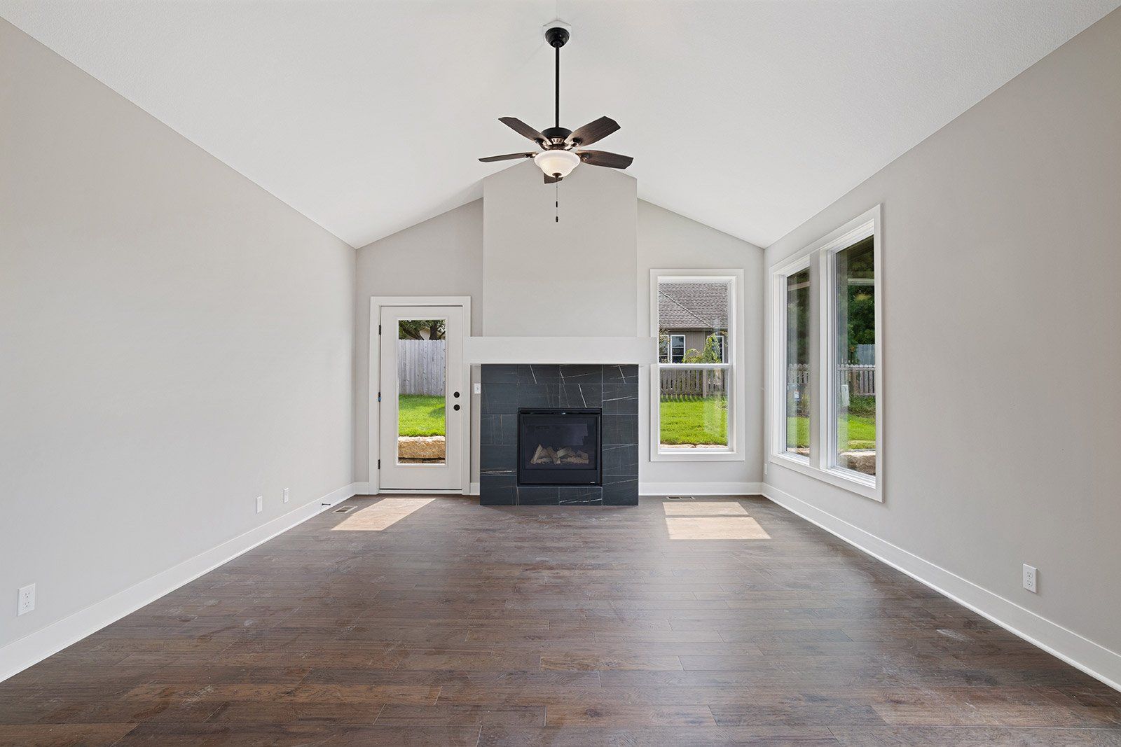 An empty living room with a fireplace and ceiling fan.