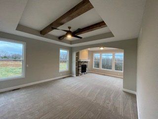 An empty living room with a fireplace and ceiling fan.
