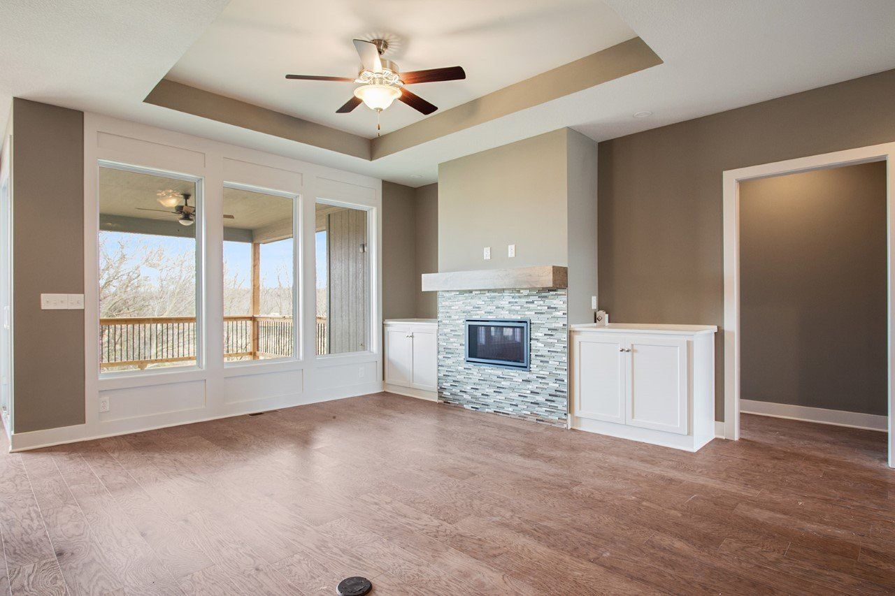 An empty living room with a fireplace and a ceiling fan.