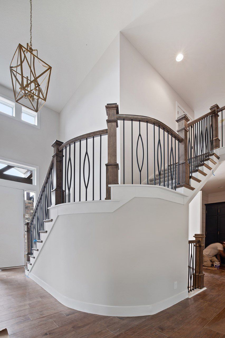 A curved staircase in a house with a chandelier hanging from the ceiling.