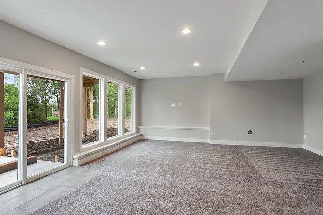 An empty basement with a lot of windows and a carpeted floor.