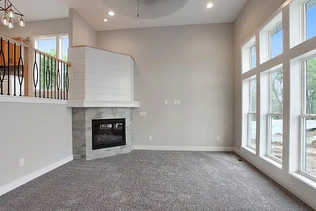 An empty living room with a fireplace and lots of windows.