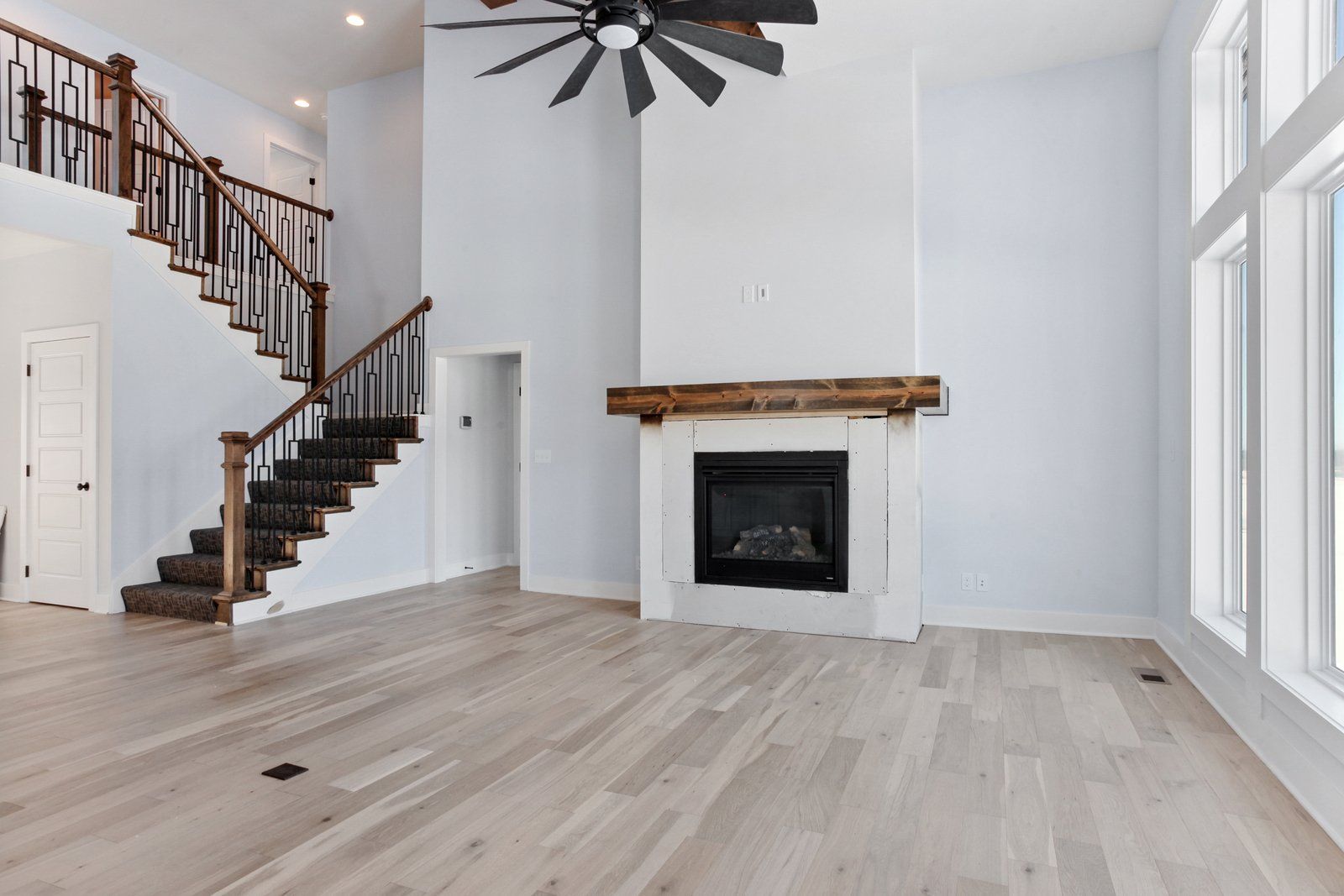 An empty living room with a fireplace and stairs.