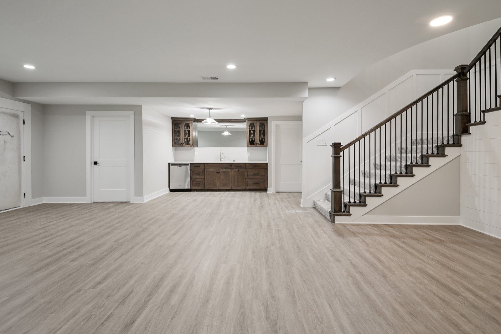 An empty basement with hardwood floors and stairs.