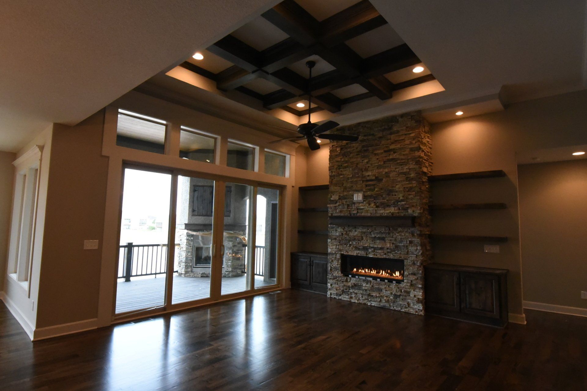 An empty living room with a fireplace and sliding glass doors.