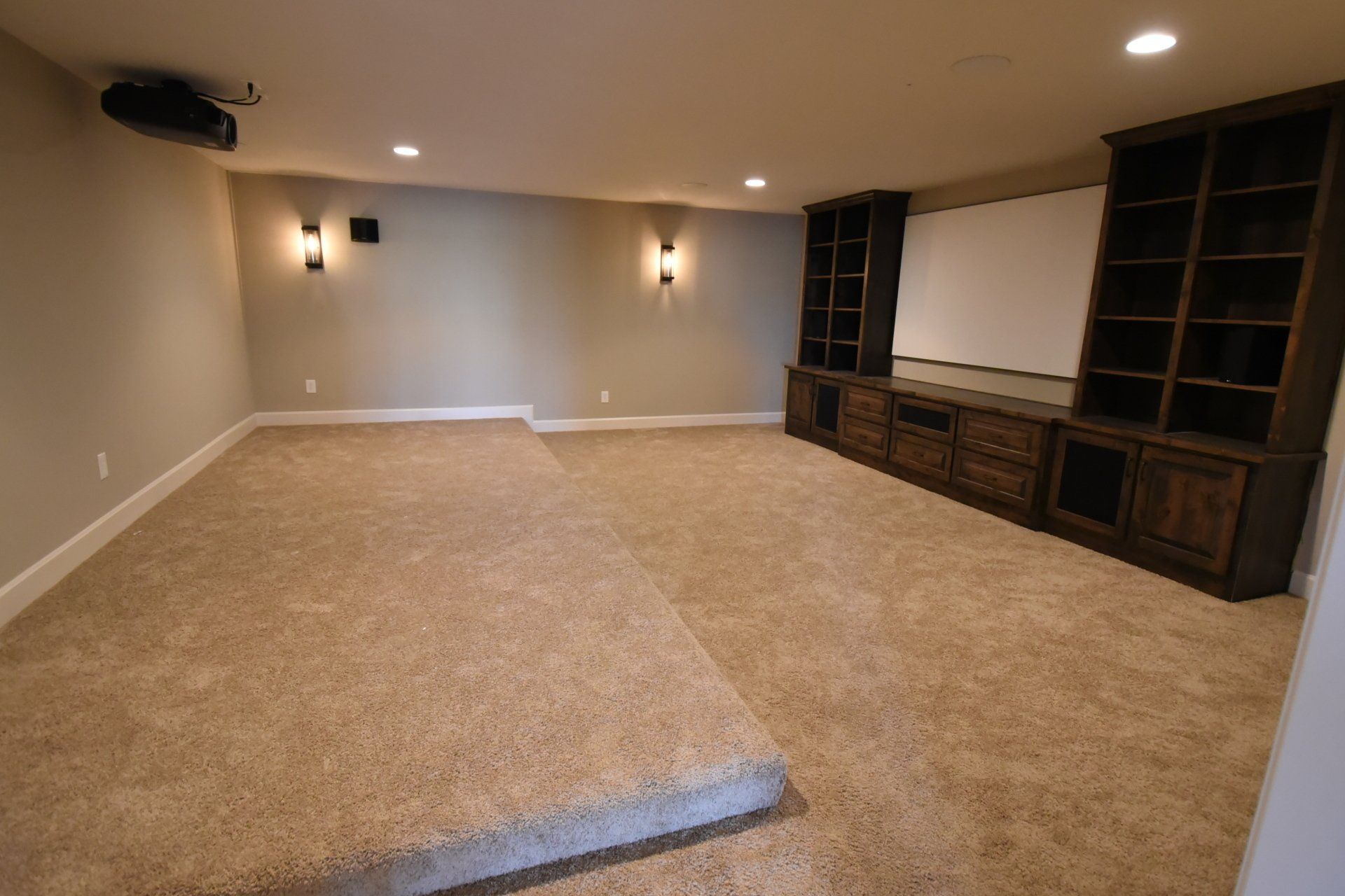 An empty basement with a projector and shelves