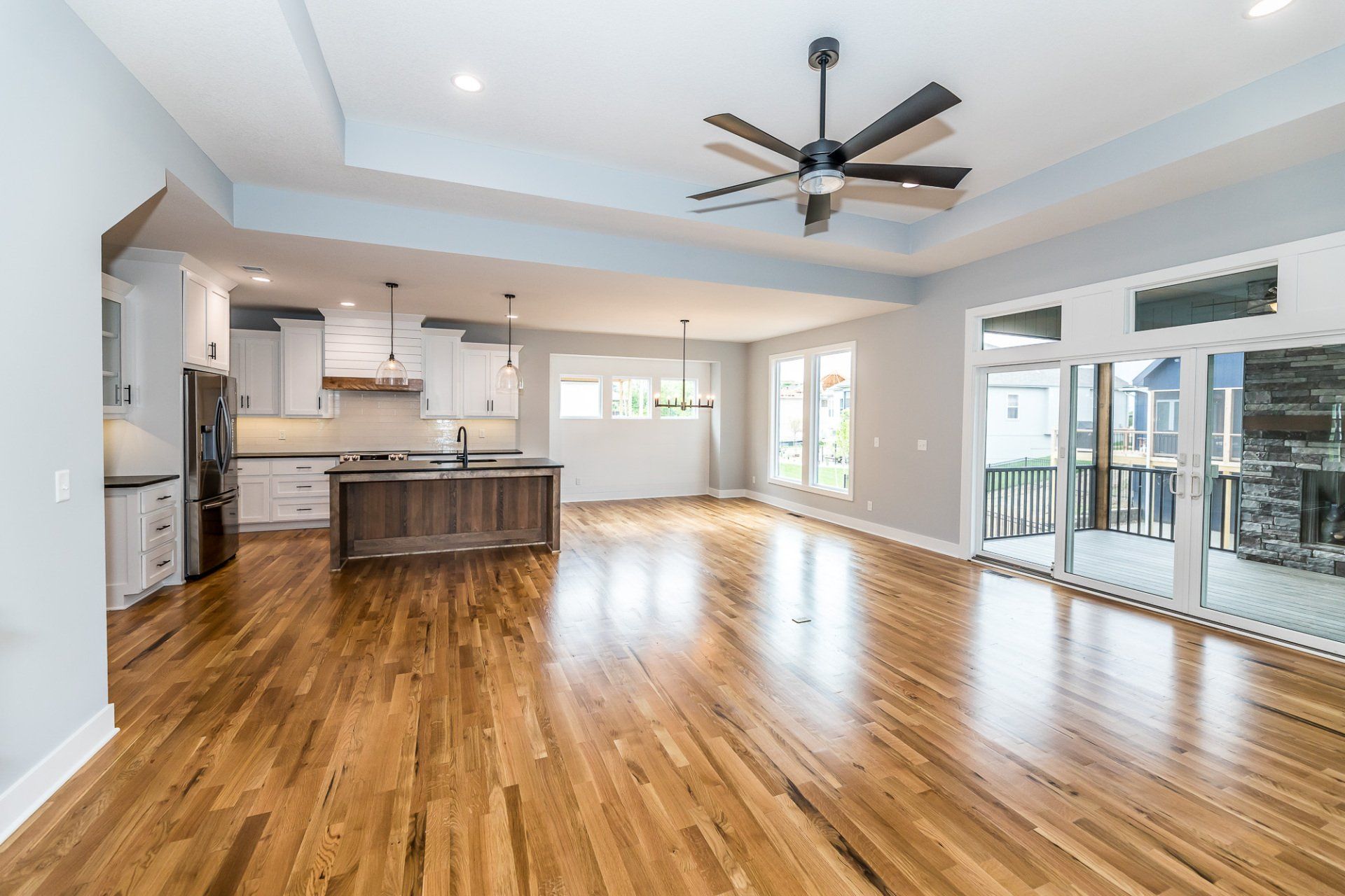 A large empty room with hardwood floors and a ceiling fan.