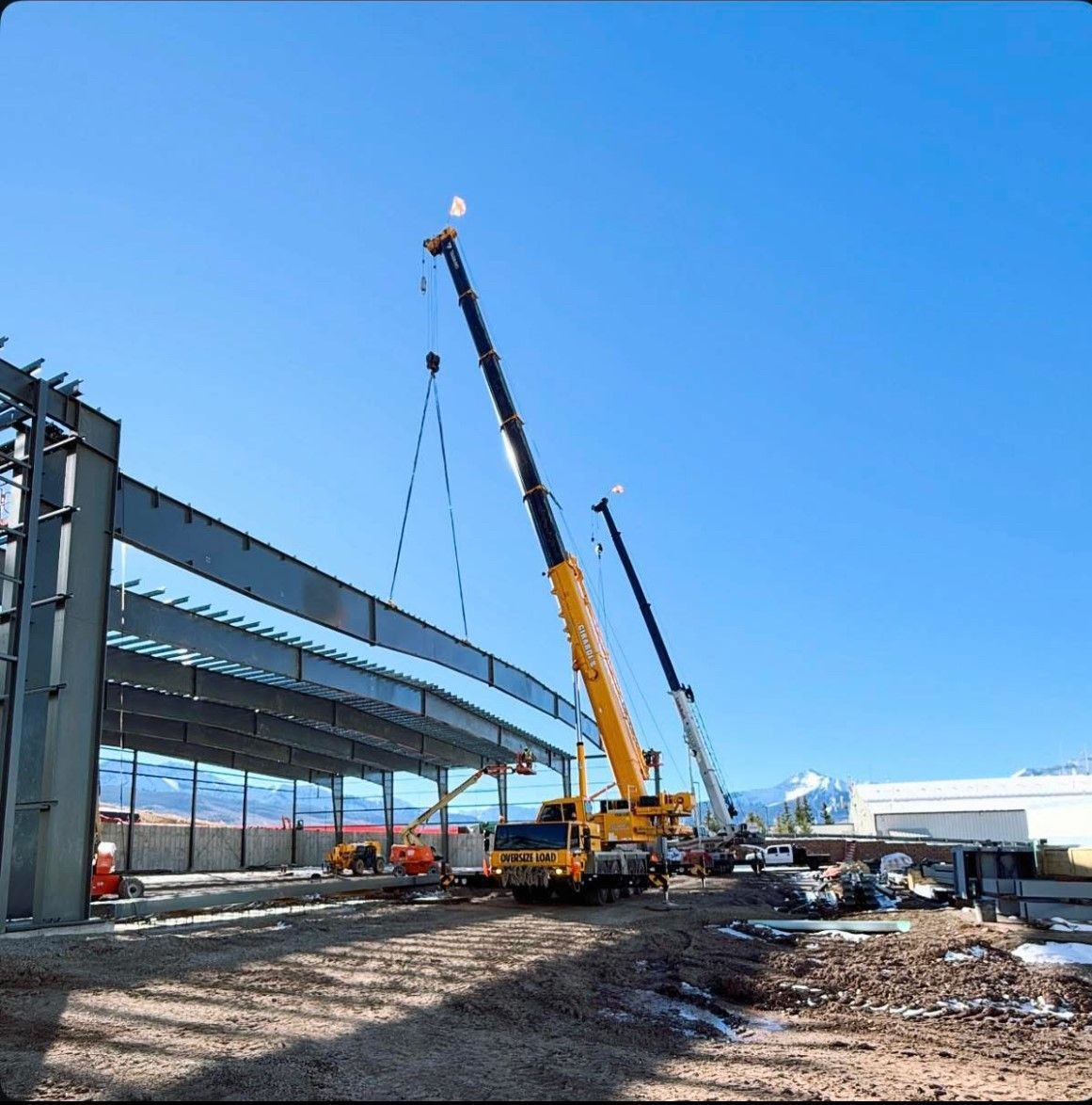 A large yellow crane is lifting a large metal structure