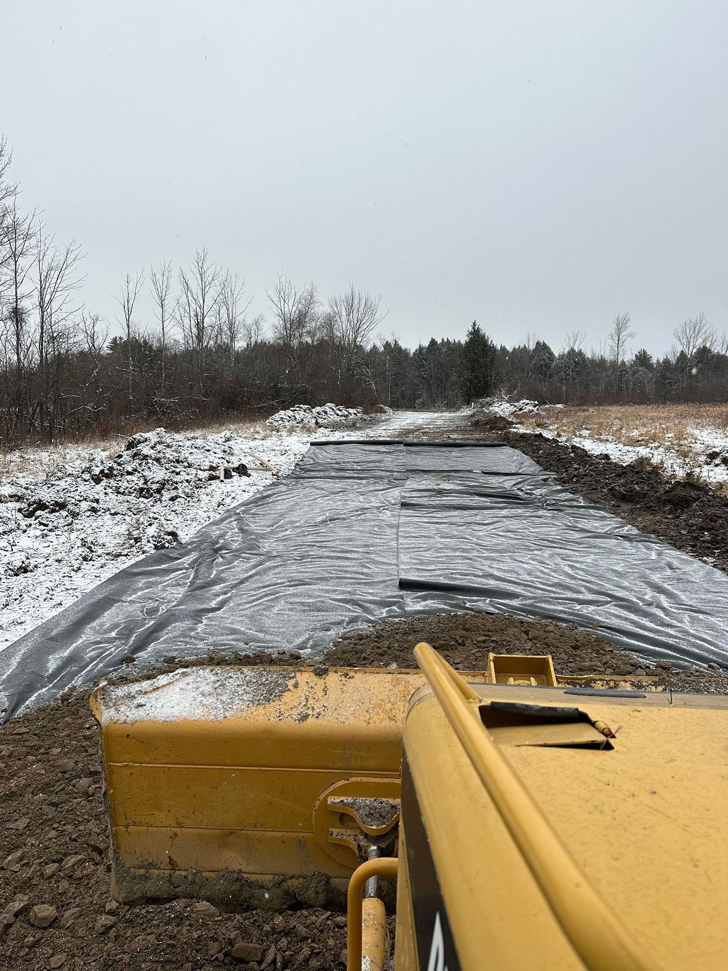 A bulldozer is moving dirt on a snowy road