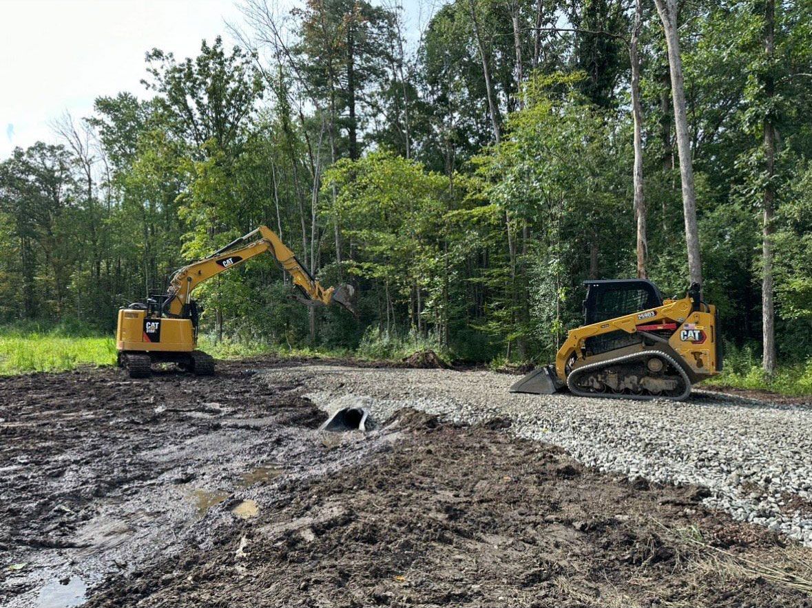 A bulldozer and an excavator are working on a dirt road