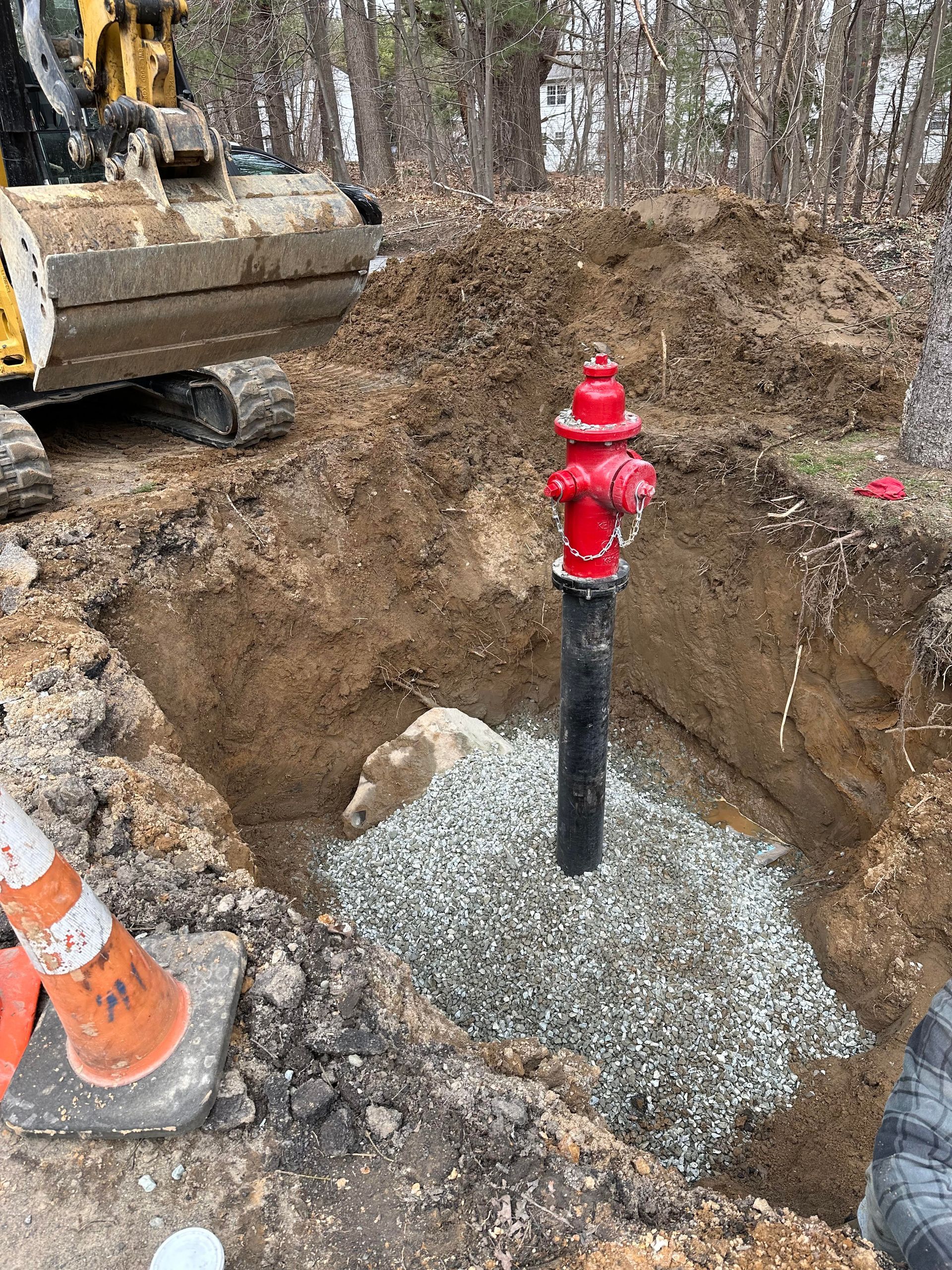 A red fire hydrant is sitting in a hole in the ground