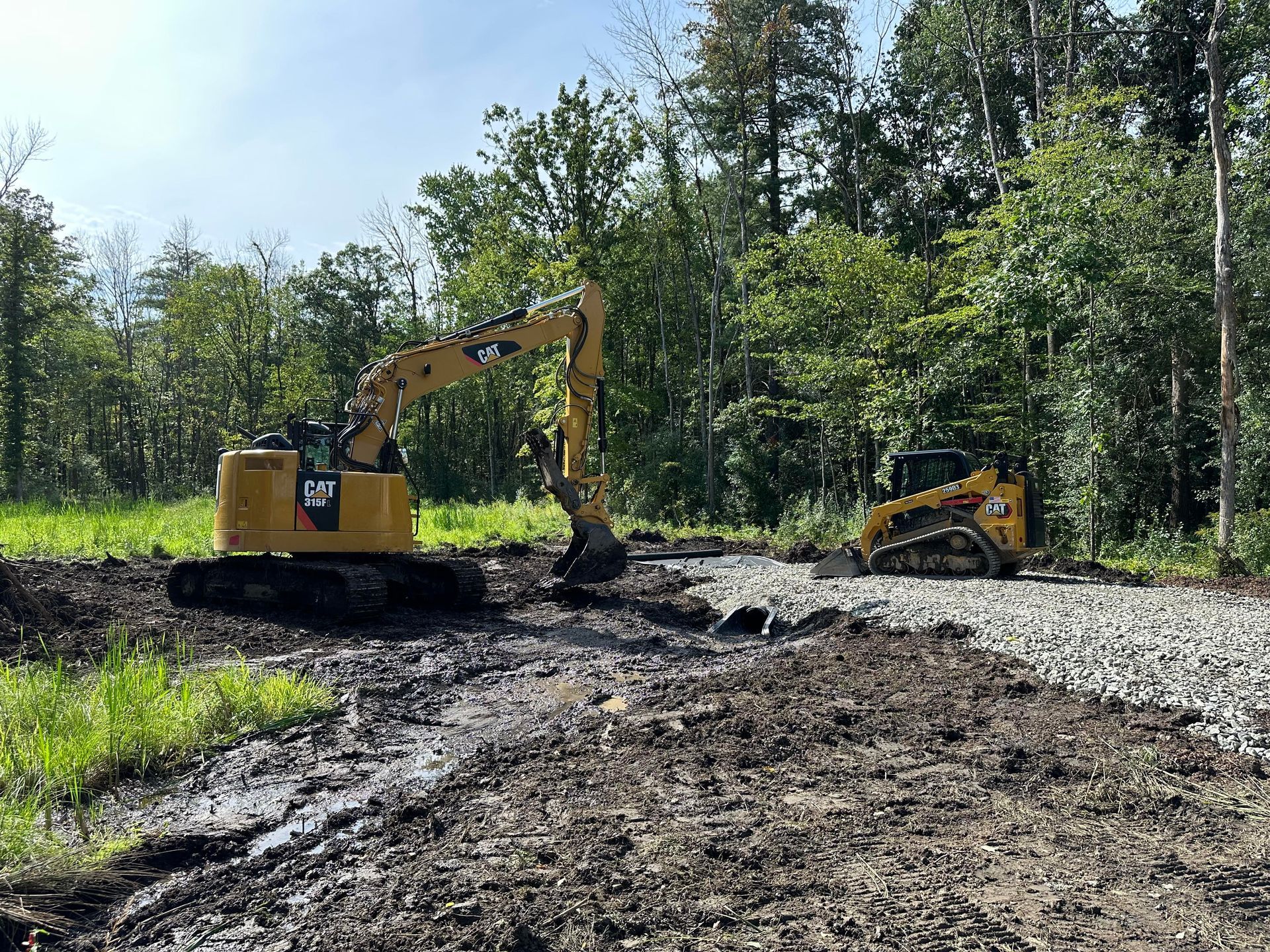 A bulldozer and an excavator are working in a muddy field