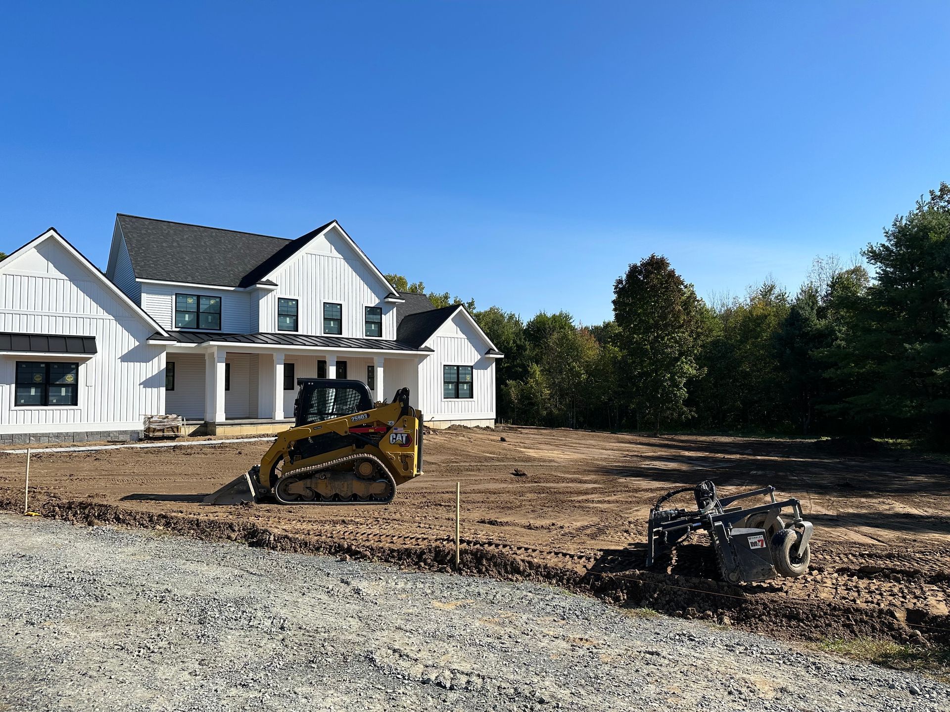A large white house is being built with a bulldozer in front of it