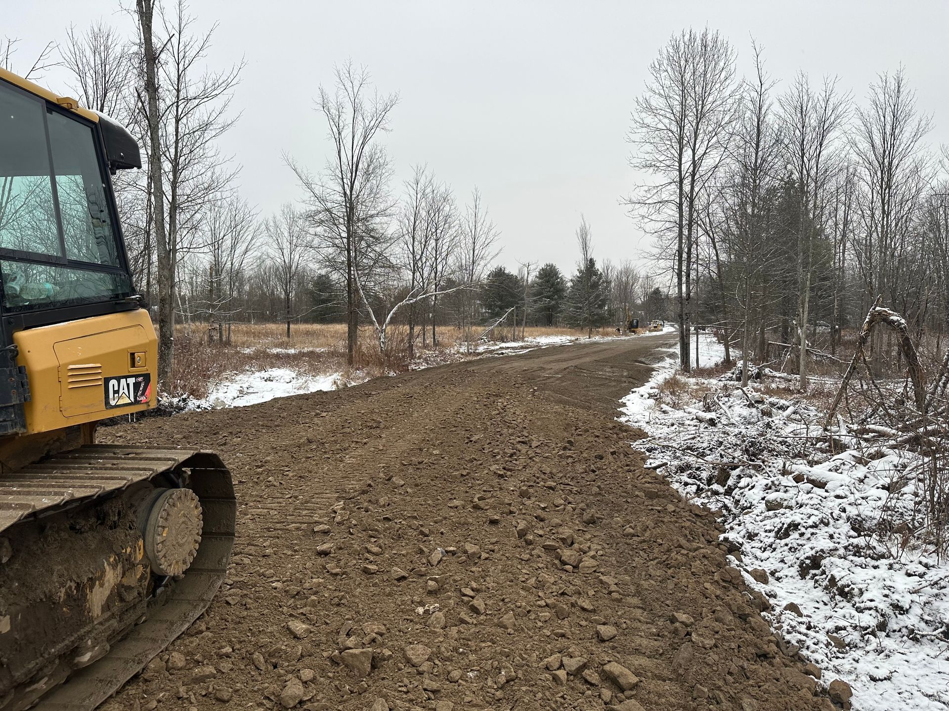 A yellow bulldozer is driving down a dirt road