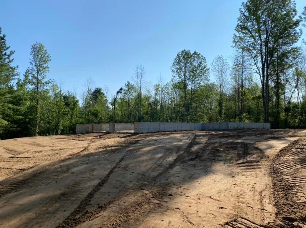 A dirt road with trees in the background and a blue sky