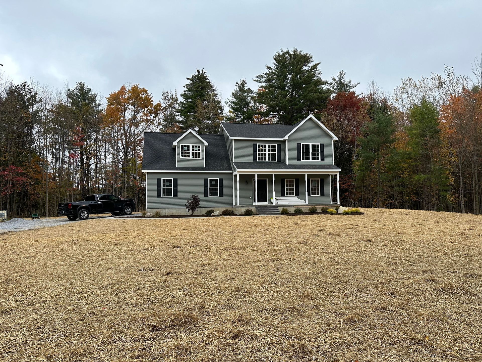 A large house is sitting in the middle of a field surrounded by trees