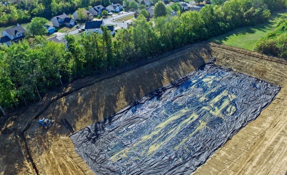 An aerial view of a large dirt field with trees in the background