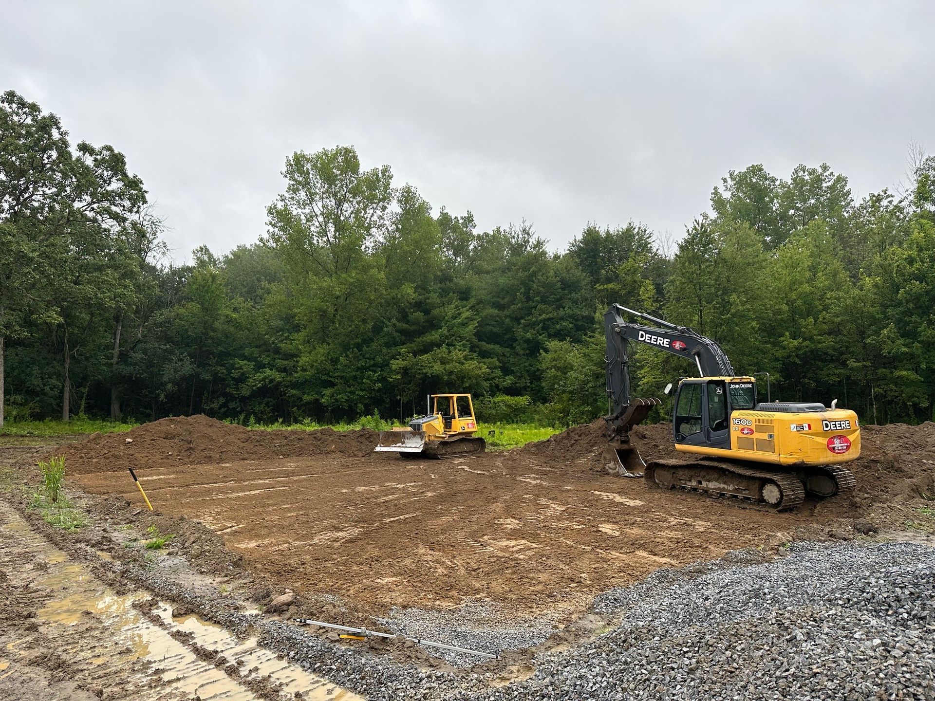 A bulldozer and an excavator are working in a dirt field