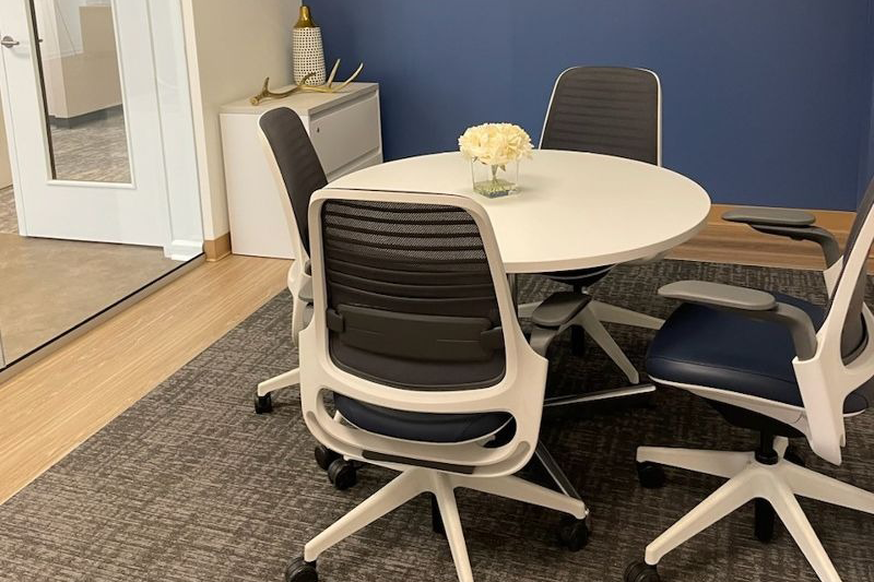A conference room with a round table and chairs.