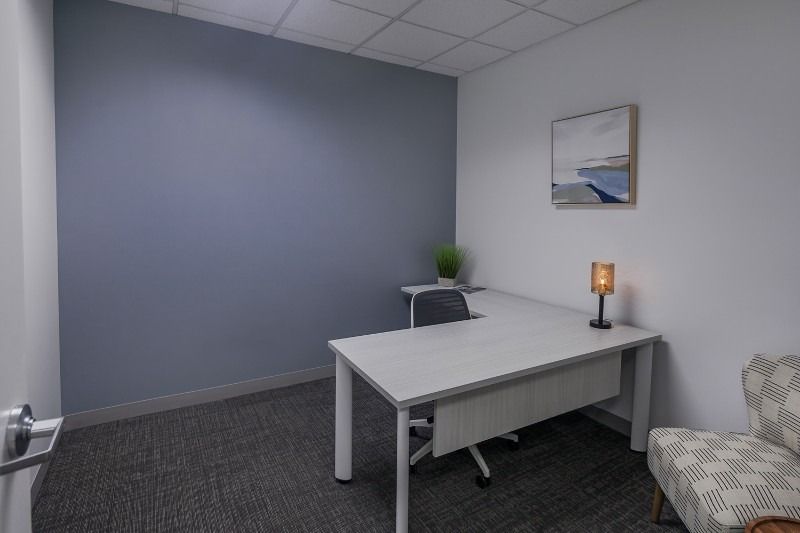 A small office with a desk , chair and lamp.