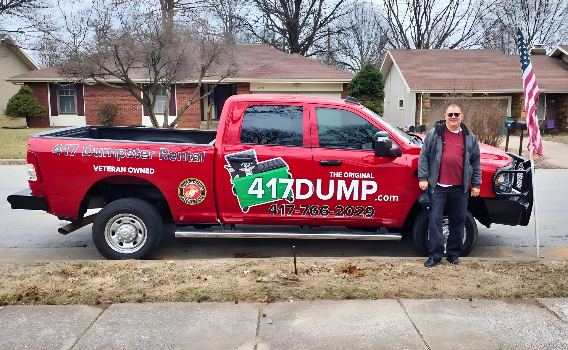 Man stands by a red pickup truck with 