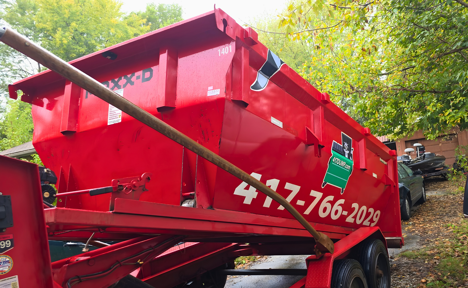 Red dumpster on a trailer with phone number 417-766-2029 visible.