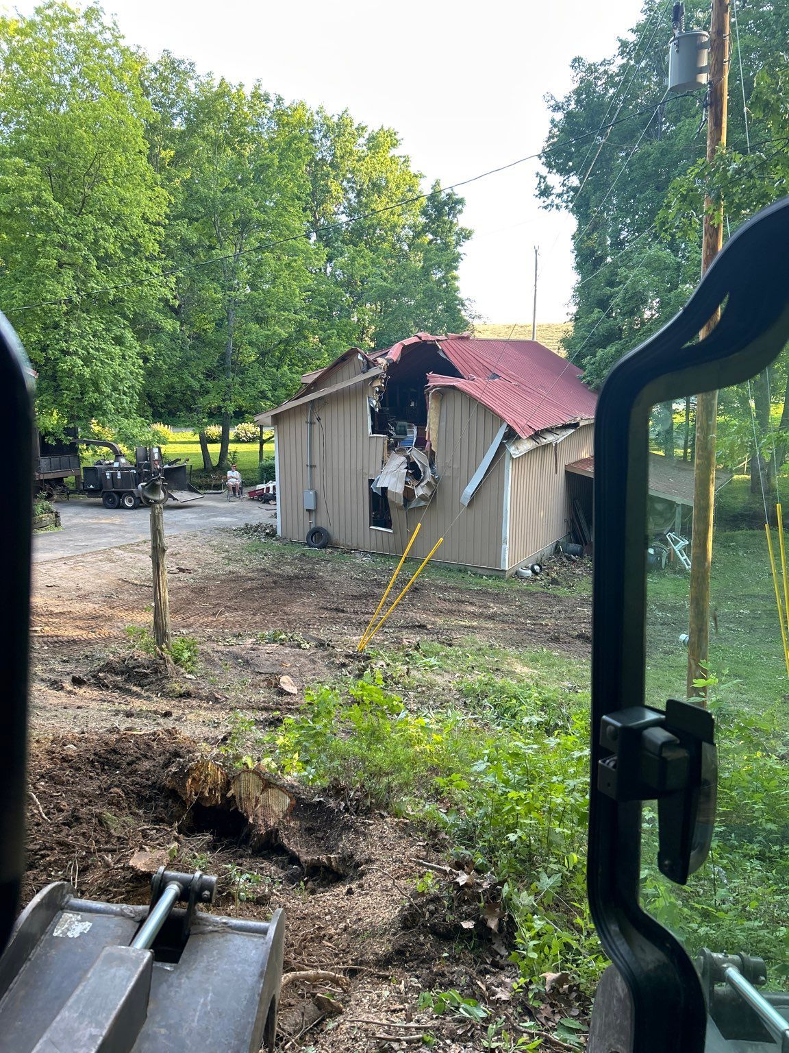 A tractor is sitting in front of a house that has been demolished.