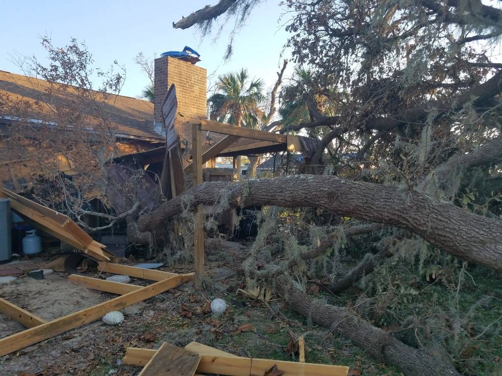 A large tree has fallen on top of a house.