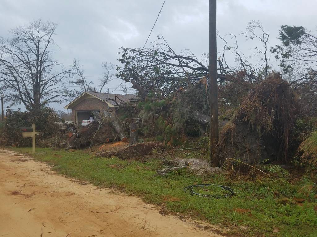 A dirt road leading to a house with a cross in the middle of it.