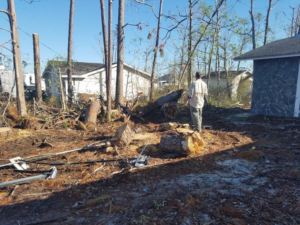 A man is standing in a yard with trees and a shed in the background.